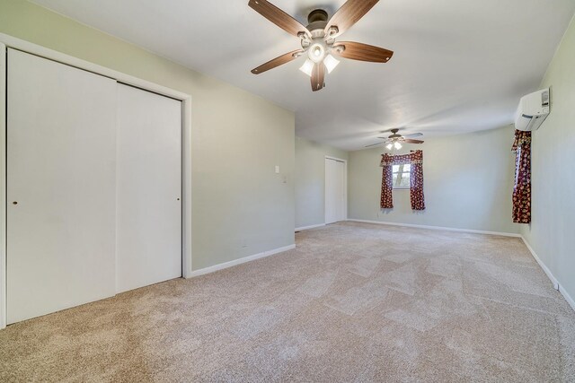 unfurnished bedroom with a ceiling fan, light colored carpet, a wall unit AC, and baseboards