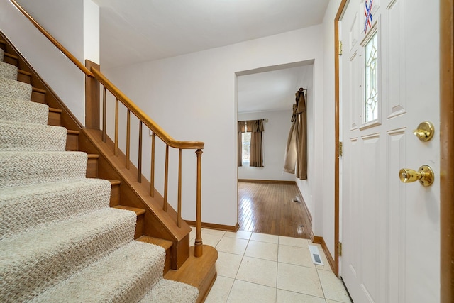 entryway with light tile patterned floors, stairs, visible vents, and baseboards