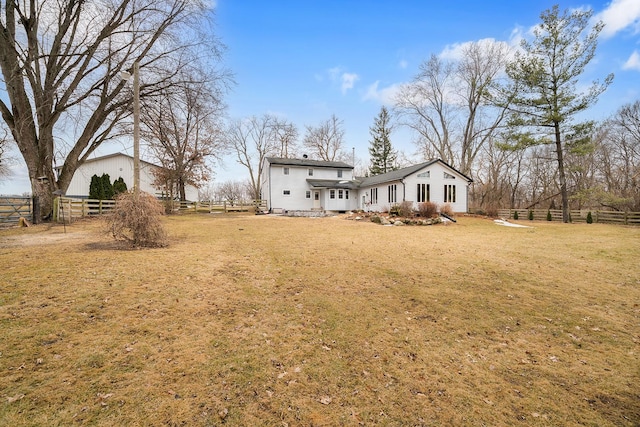 rear view of house featuring a yard and fence