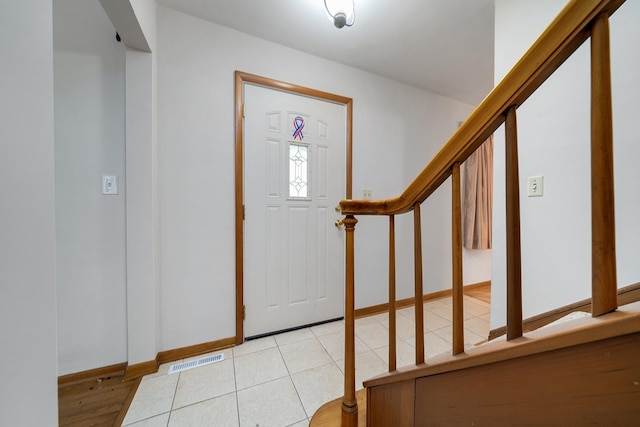 entryway with light tile patterned floors, stairs, visible vents, and baseboards