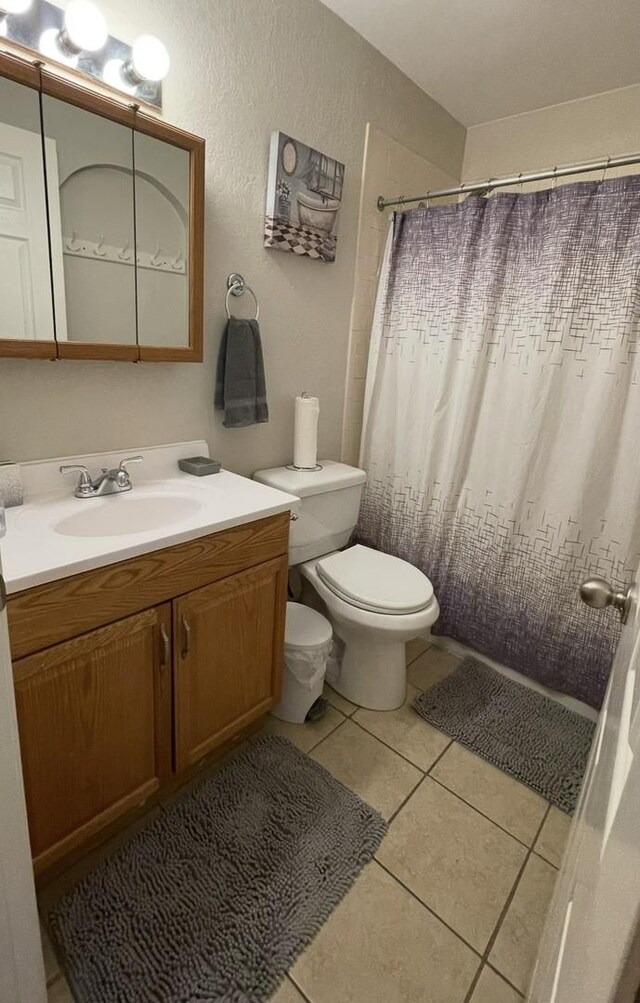 bathroom featuring a shower with shower curtain, vanity, toilet, and tile patterned floors