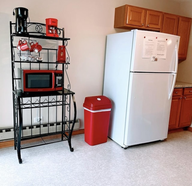 kitchen featuring brown cabinetry, freestanding refrigerator, a baseboard heating unit, and light floors