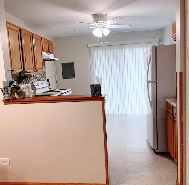 kitchen featuring white appliances, electric panel, a ceiling fan, brown cabinets, and under cabinet range hood