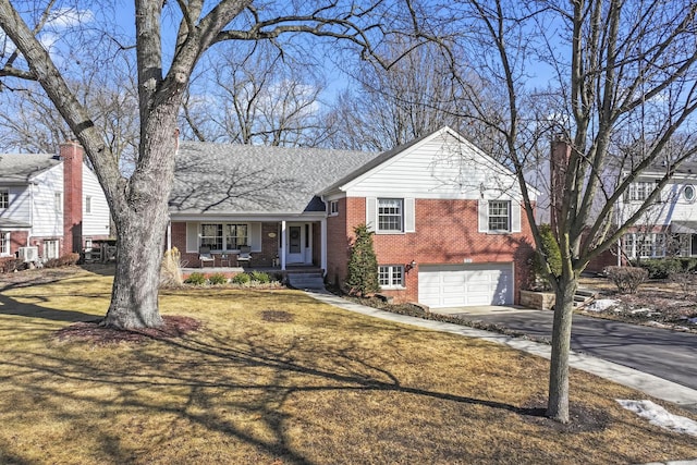 tri-level home with a porch, concrete driveway, brick siding, and an attached garage