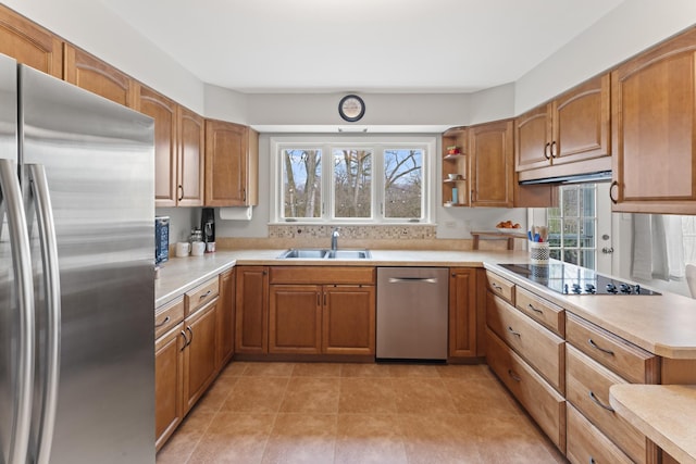 kitchen featuring stainless steel appliances, brown cabinets, a healthy amount of sunlight, and a sink