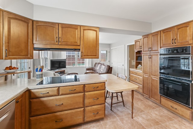 kitchen featuring black appliances, brown cabinetry, light tile patterned flooring, and light countertops