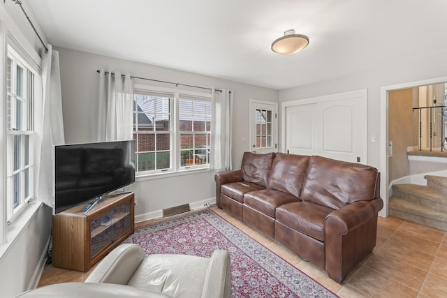 tiled living room with stairs and baseboards