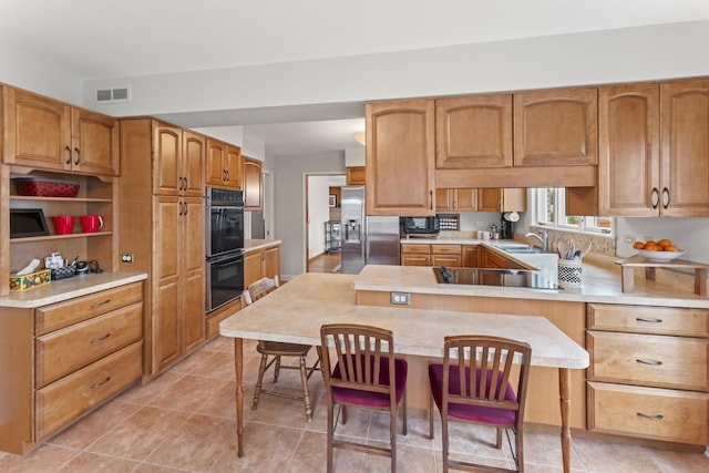 kitchen featuring visible vents, light countertops, a sink, a peninsula, and black appliances