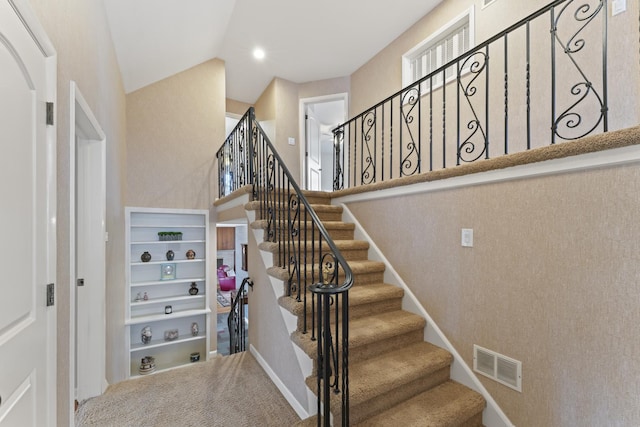 stairs with carpet floors, visible vents, vaulted ceiling, and baseboards