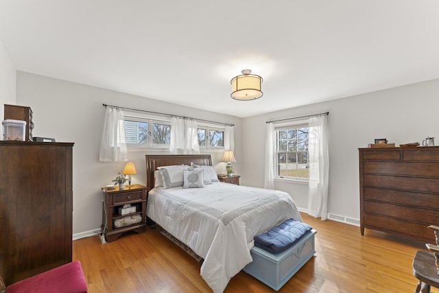 bedroom with light wood-type flooring, visible vents, and baseboards