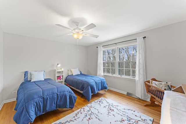 bedroom with visible vents, wood finished floors, a ceiling fan, and baseboards