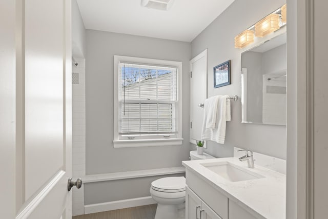 bathroom featuring vanity, walk in shower, toilet, and baseboards