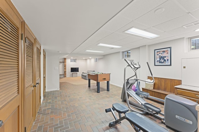 workout room with brick floor, baseboards, visible vents, and a drop ceiling