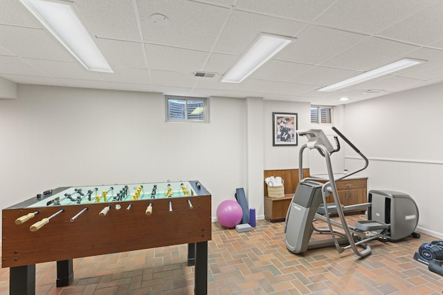 interior space featuring brick floor, visible vents, and a drop ceiling