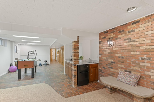 interior space featuring brick floor, brick wall, and a sink