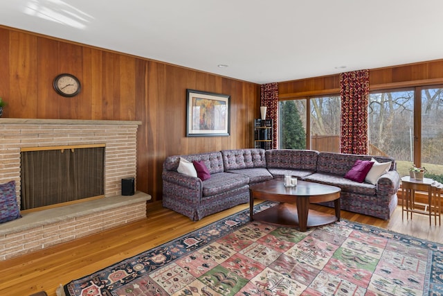 living area featuring a brick fireplace, wood finished floors, and wooden walls