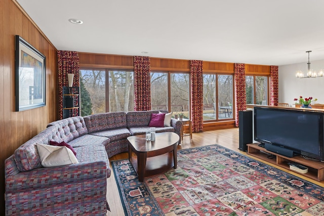 living area featuring wood walls, light wood-style flooring, and a chandelier