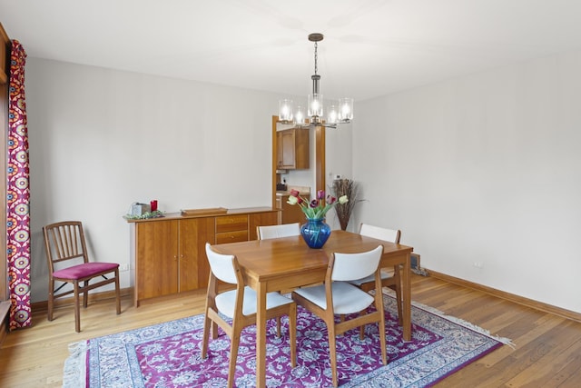 dining space featuring light wood-type flooring, baseboards, and a chandelier