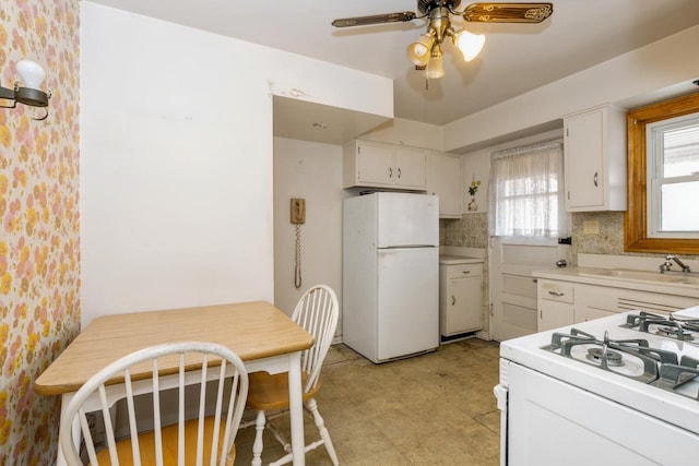 kitchen with white appliances, tasteful backsplash, a ceiling fan, light countertops, and white cabinetry