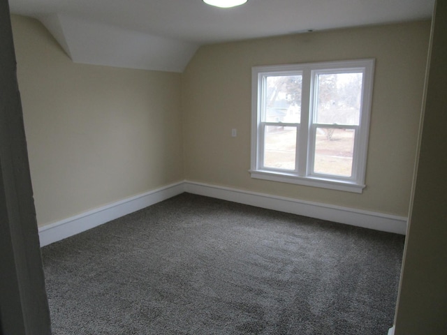 bonus room featuring lofted ceiling, dark colored carpet, and baseboards