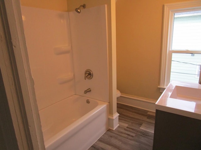 full bathroom with toilet, wood finished floors, vanity, baseboards, and washtub / shower combination