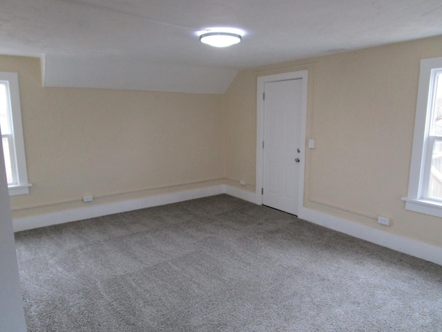 carpeted empty room with plenty of natural light, baseboards, and vaulted ceiling