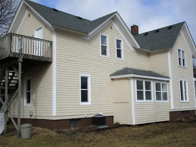 back of property with a wooden deck, a chimney, cooling unit, and roof with shingles