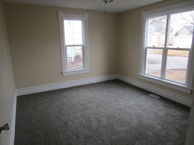 empty room featuring carpet floors, visible vents, and baseboards