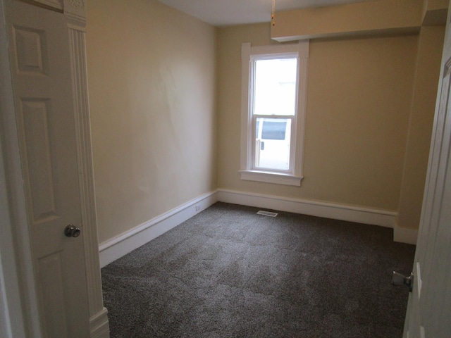 spare room with carpet floors, visible vents, and baseboards