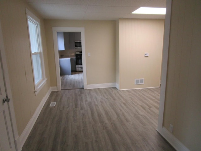 unfurnished room with visible vents, a drop ceiling, baseboards, and wood finished floors