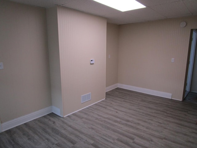 empty room featuring baseboards, visible vents, a drop ceiling, and wood finished floors