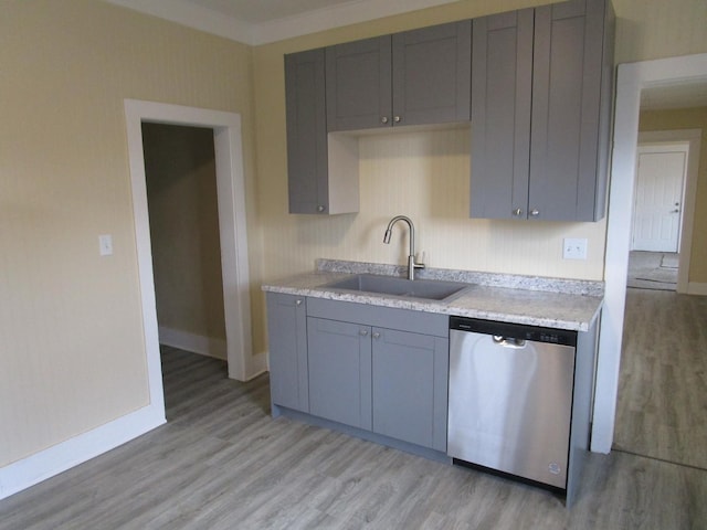 kitchen with light wood-style flooring, gray cabinetry, a sink, light countertops, and dishwasher