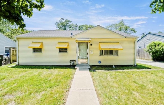 bungalow-style home with fence and a front yard