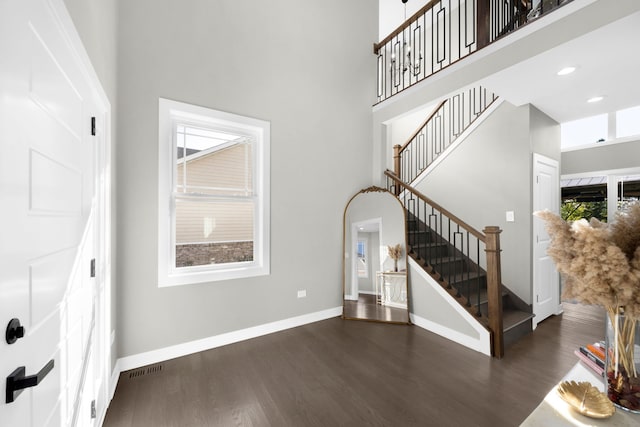 living area featuring baseboards, stairway, a high ceiling, and wood finished floors