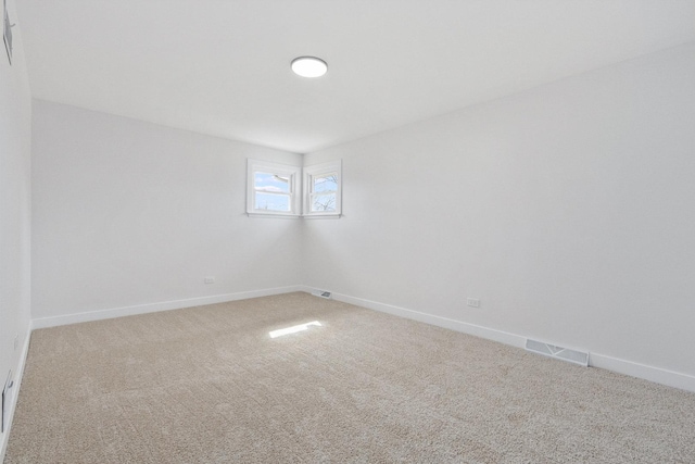 spare room with carpet, visible vents, and baseboards