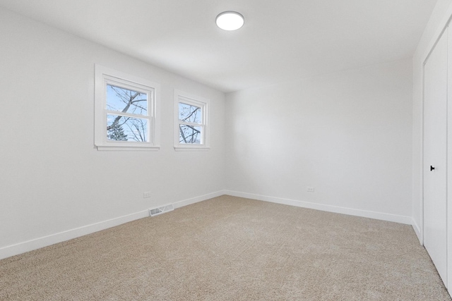 interior space with baseboards, visible vents, and light colored carpet