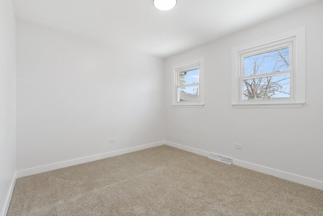 empty room featuring carpet, visible vents, and baseboards