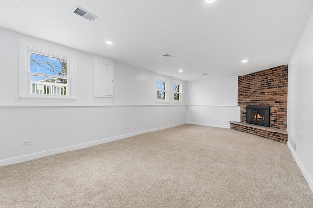 unfurnished living room featuring recessed lighting, light carpet, visible vents, baseboards, and a brick fireplace