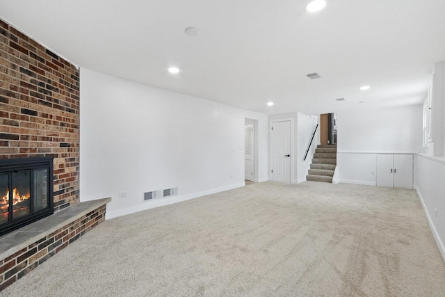 interior space with baseboards, visible vents, stairs, carpet floors, and a brick fireplace