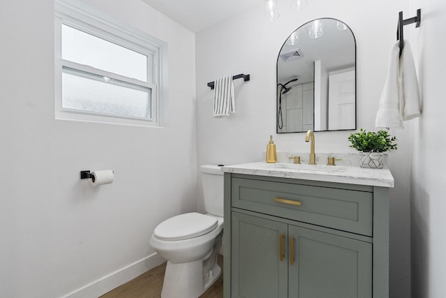 bathroom with visible vents, toilet, vanity, wood finished floors, and baseboards