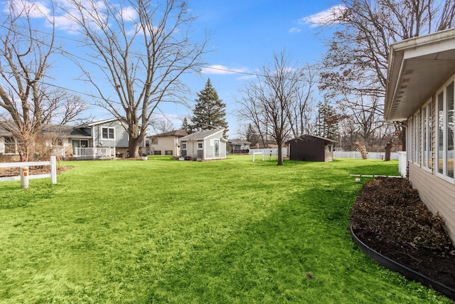 view of yard featuring a residential view, an outdoor structure, a shed, and fence