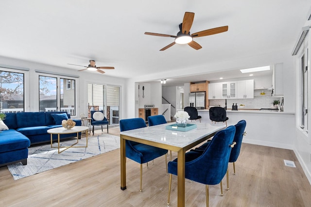 dining space featuring light wood finished floors, baseboards, and a ceiling fan