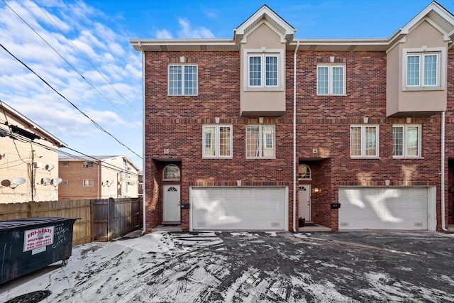 multi unit property featuring a garage, fence, and brick siding