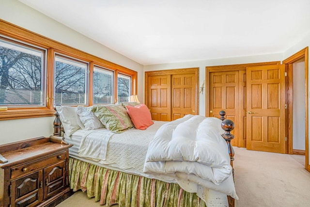 bedroom featuring multiple closets and light carpet