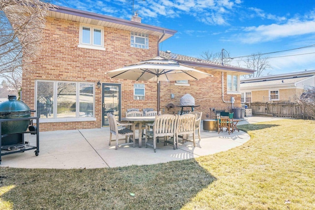 back of property featuring brick siding, a lawn, a chimney, and fence