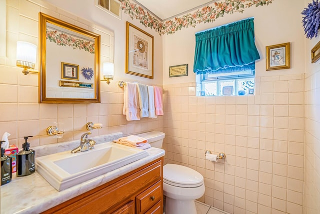 bathroom featuring vanity, tile walls, toilet, and visible vents