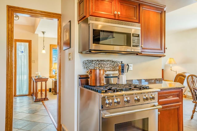 kitchen featuring light tile patterned floors, baseboards, appliances with stainless steel finishes, and light countertops