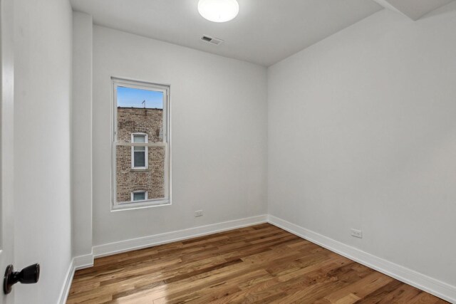 spare room featuring visible vents, baseboards, and wood finished floors