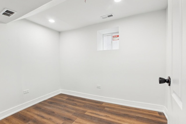 unfurnished room featuring dark wood-type flooring, visible vents, and baseboards