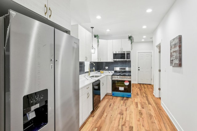 kitchen with white cabinets, decorative backsplash, stainless steel appliances, light countertops, and a sink